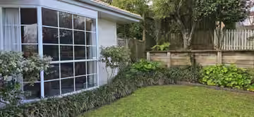 Customer photo of a maintained lawn and shaped garden shrubs